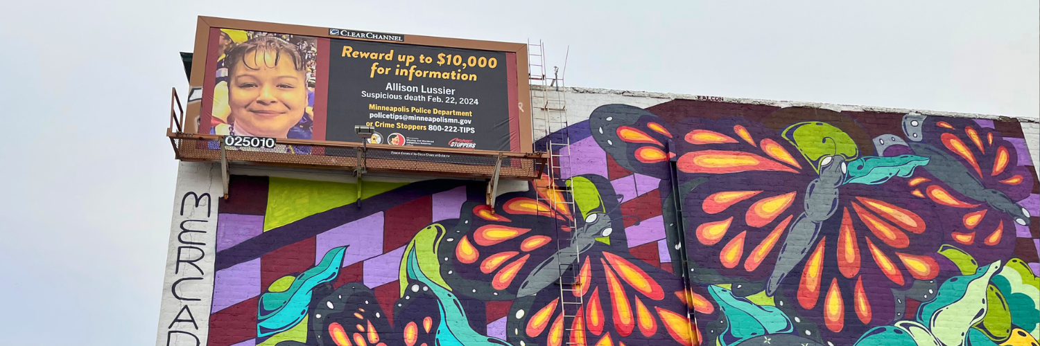 Allison Lussier billboard above a colorful mural in South Minneapolis.