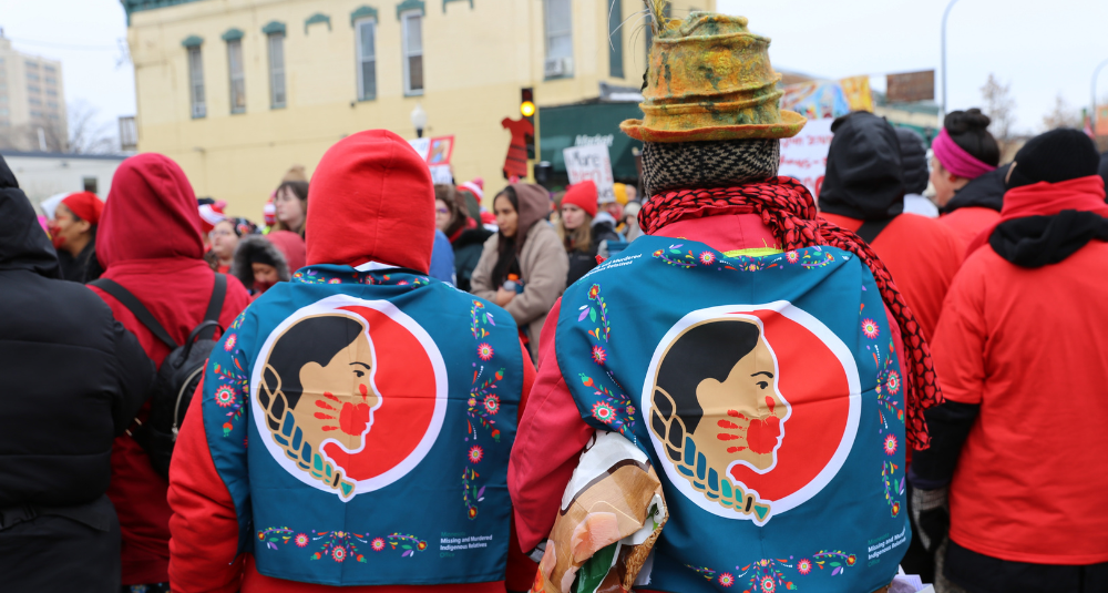 Two women wear the MMIR bandanas on their backs.