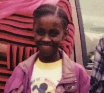 Young black girl in purple jacket smiliing