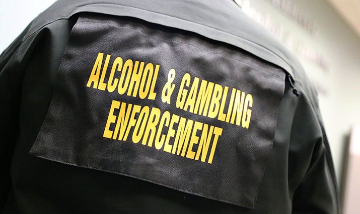 The words "Alcohol & Gambling Enforcement" on the back of an agent's jacket.