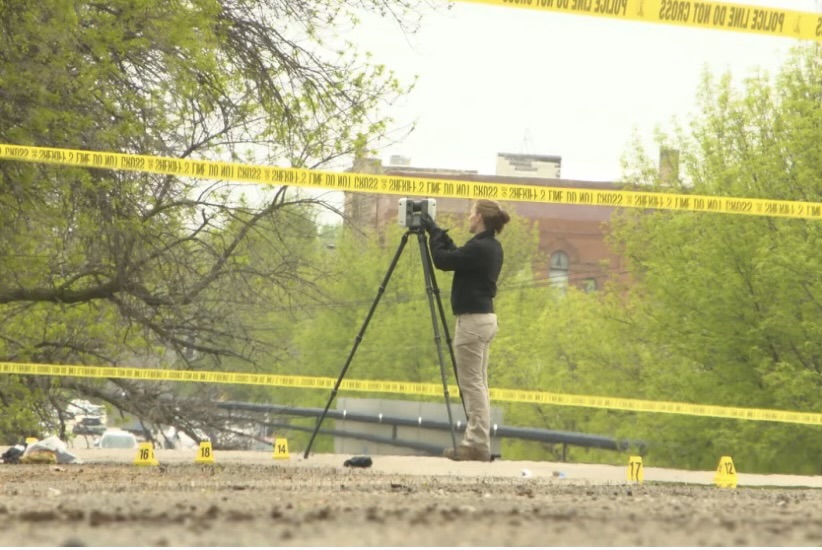 A scientist using a 3D scanner outside at a crime scene