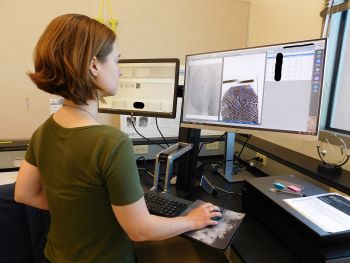 A scientist in front of computer monitors looking at fingerprints