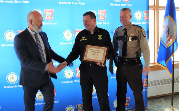 DPS Commissioner Bob Jacobson shakes hands with paramedic Jason Wiskow as Col. Matt Langer watches during the awards ceremony.