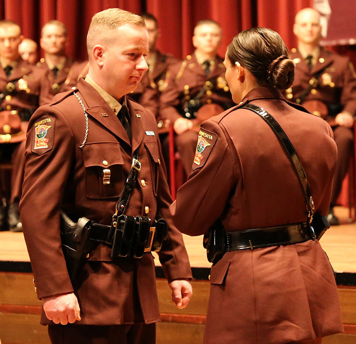 Trooper Sarah Vaagenes, right, presents her husband, Trooper Tim Vaagenes, with his badge Tuesday during the Minnesota State Patrol Academy graduation ceremony.