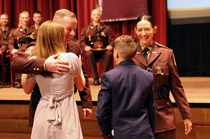Trooper Tim Vaagenes hugs his children Tuesday after his wife, Trooper Sarah Vaagenes, pinned his badge on his new uniform during the Minnesota State Patrol Academy graduation ceremony.