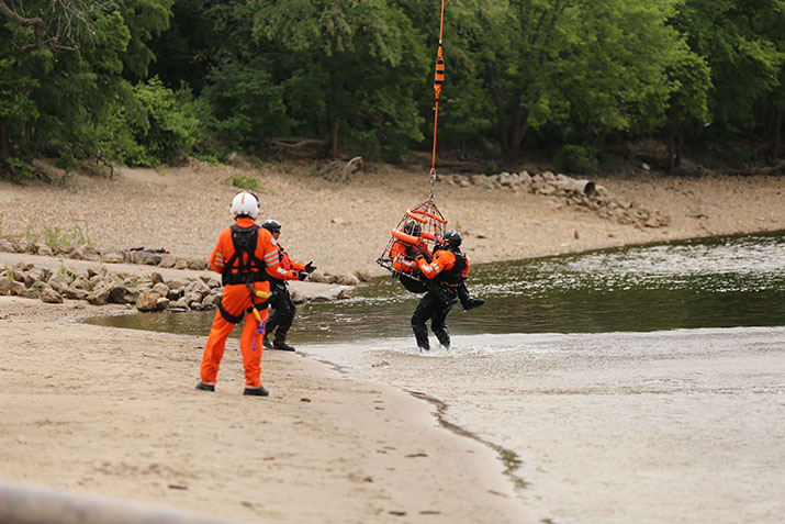 A member of the Minnesota Air Rescue Team brings a pretend victim safely to shore during water rescue training.