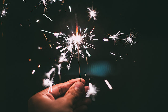 A hand holding a lit sparkler