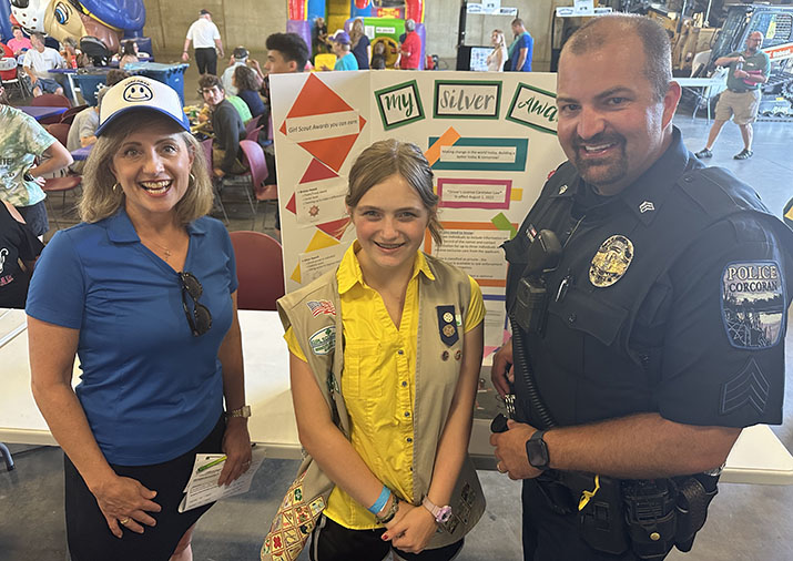 Minnesota Rep. Kristin Robbins and Corcoran Police Sgt. Pete Ekenberg with Makenna Prevost standing in front of a project display board.