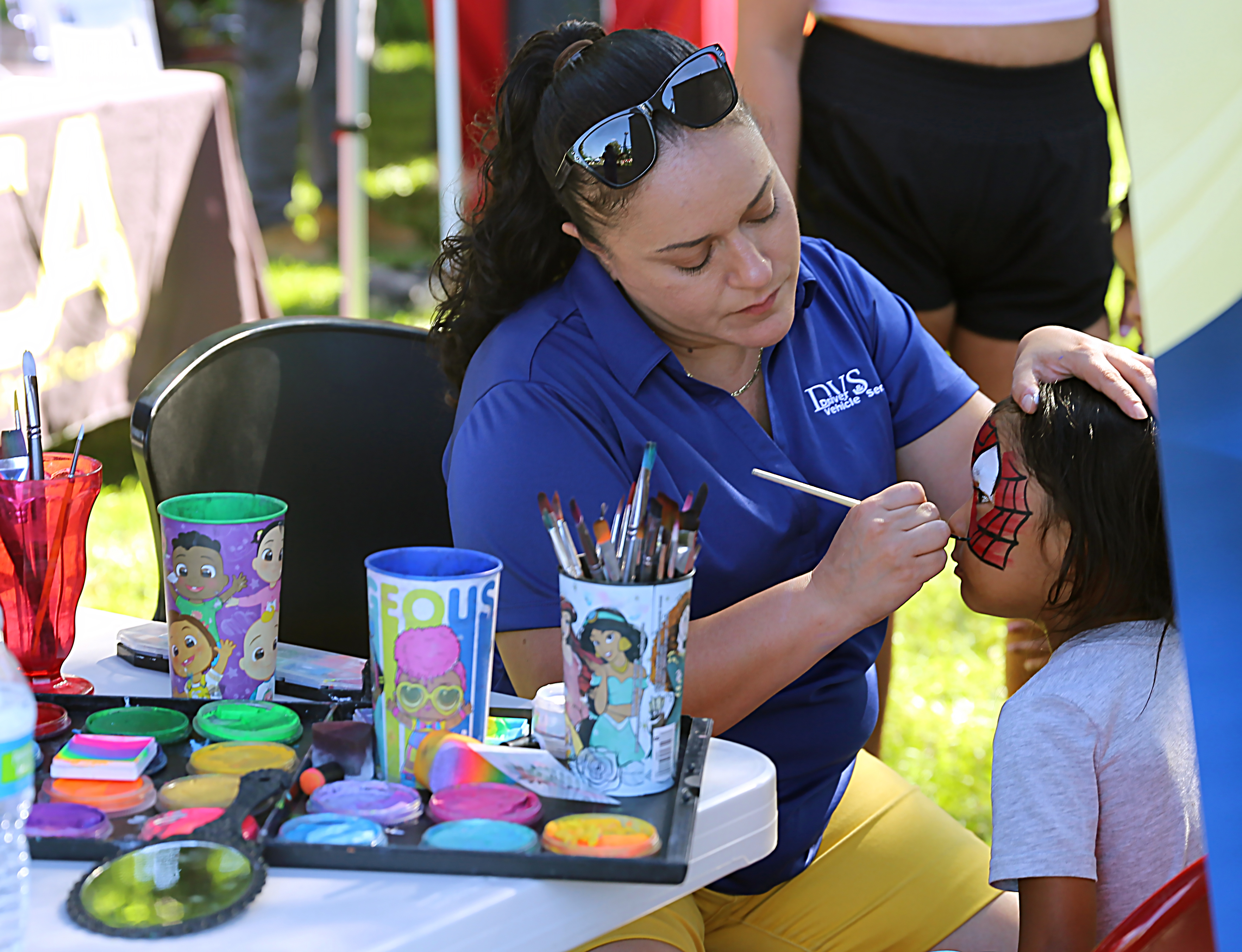A female state member paints the face of a young child. 
