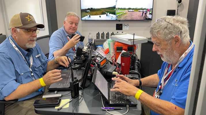 Training participants working with computers and radio equipment.