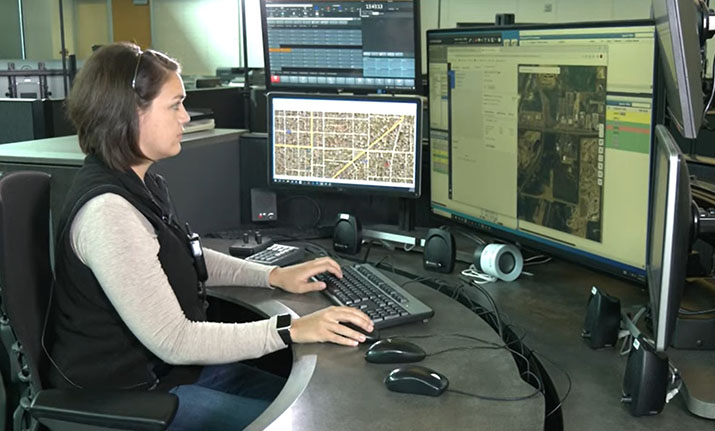 A 911 dispatcher looking at computer screens at a workstation.