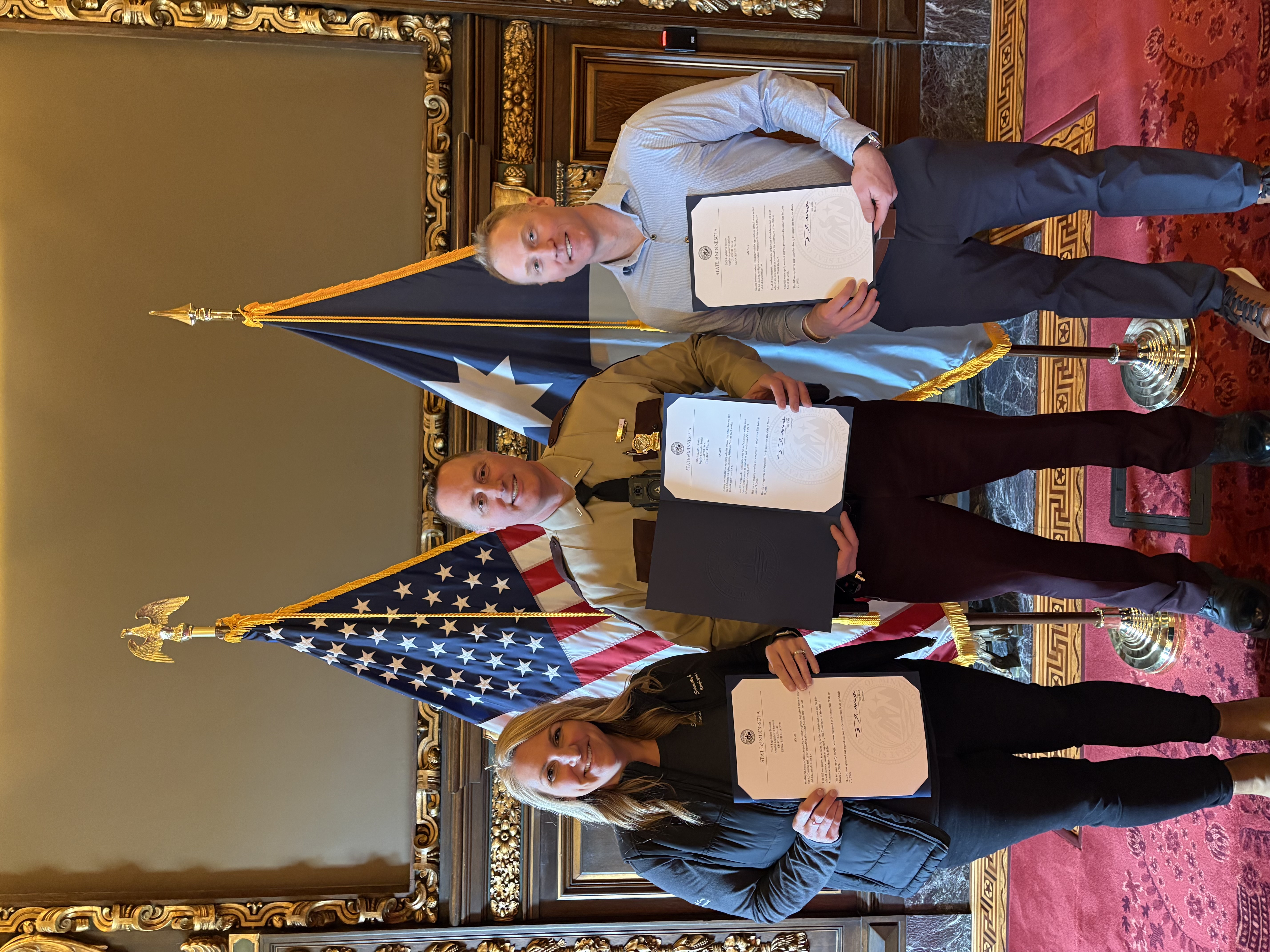 Left to right: Kathryn Forbord. President of the MInnesota School Bus Operators Association, Lt. Brian Reu of the Minnesota State Patrol and Garrett Regan of Minnesota Coaches & Affiliates pose with copies of the newly signed school bus safety law.