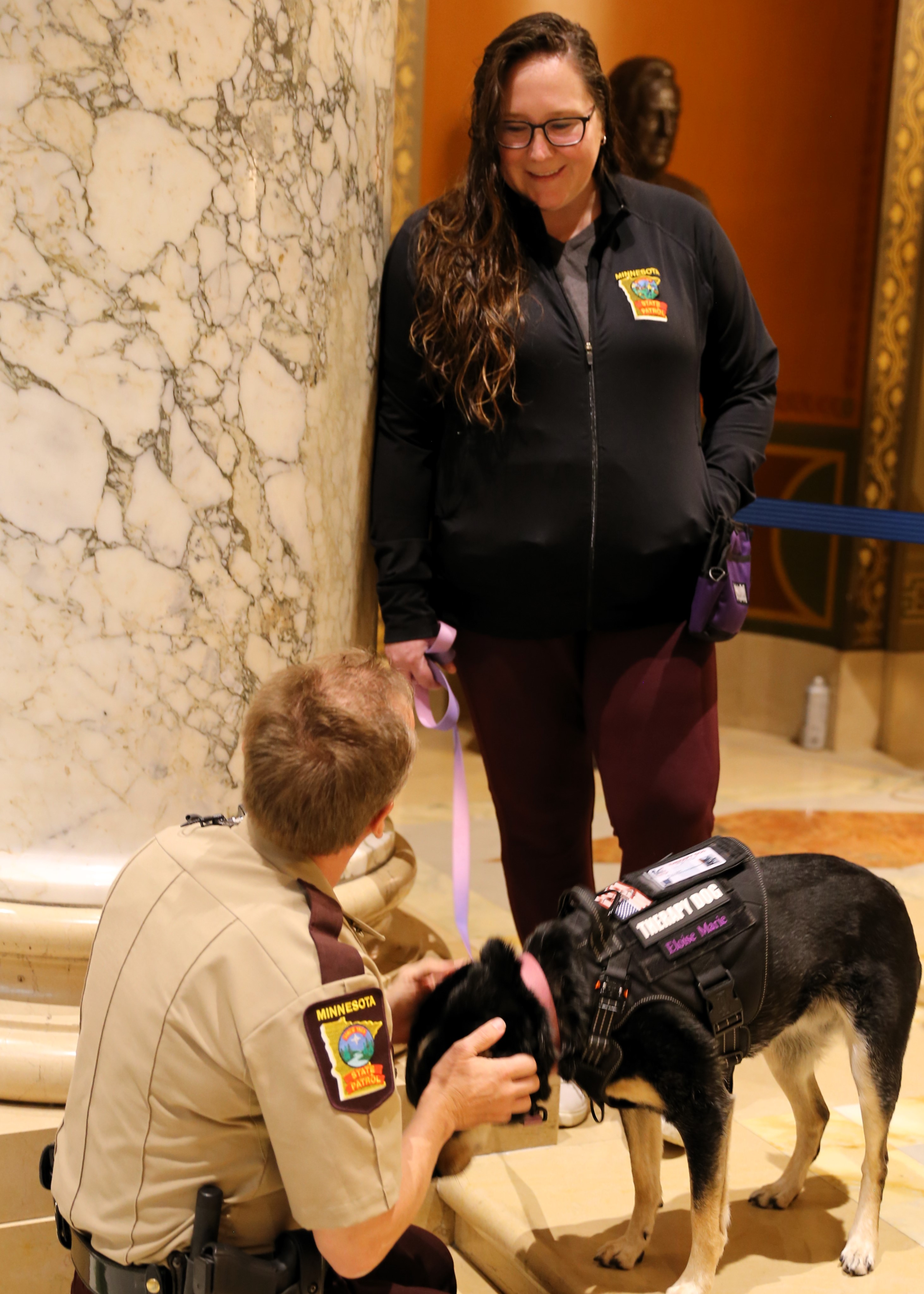 Dr. Amy Schweigert and her therapy dog, Eloise visit with a trooper at the State Capitol