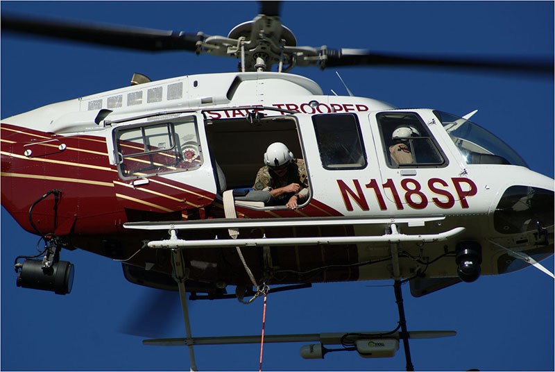 A trooper looking out the open door of a helicopter in flight