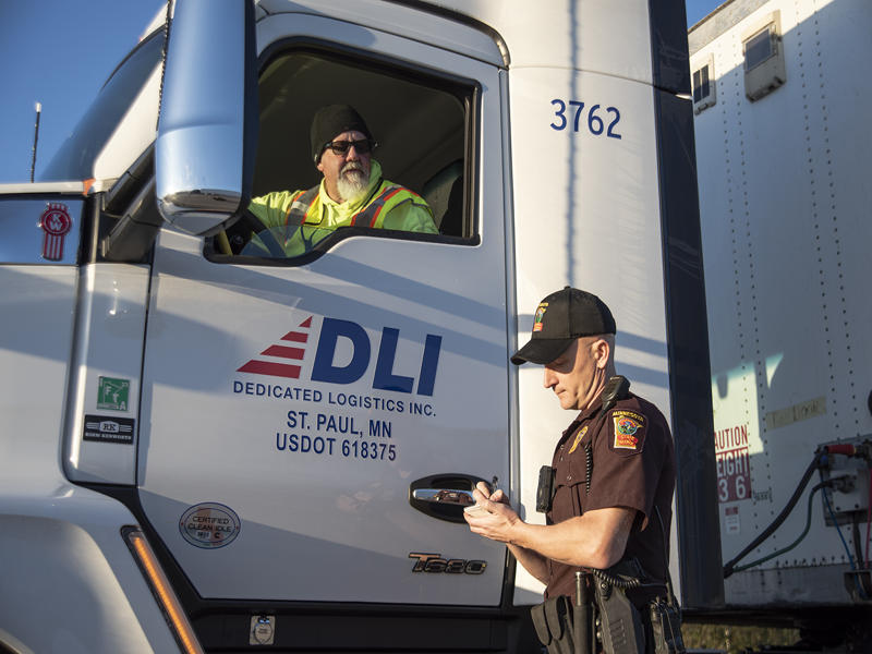 commercial vehicle inspector writing on a paper next to semi