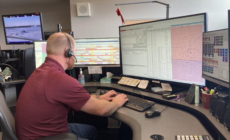 A radio communications operator wearing a headset and working at a computer.