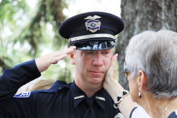 A woman puts her hands on a mourning officer's cheek.