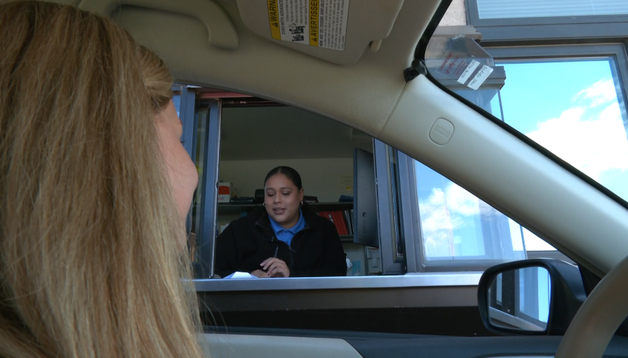 A driver pulls up to a Driver and Vehicle Services window.