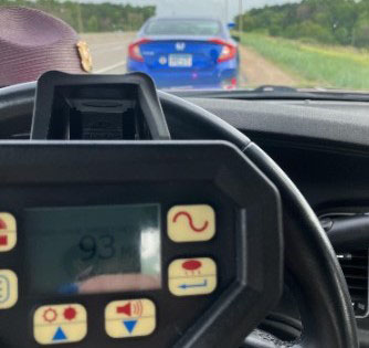 A radar gun showing 93 mph and a stopped vehicle in front of the squad car