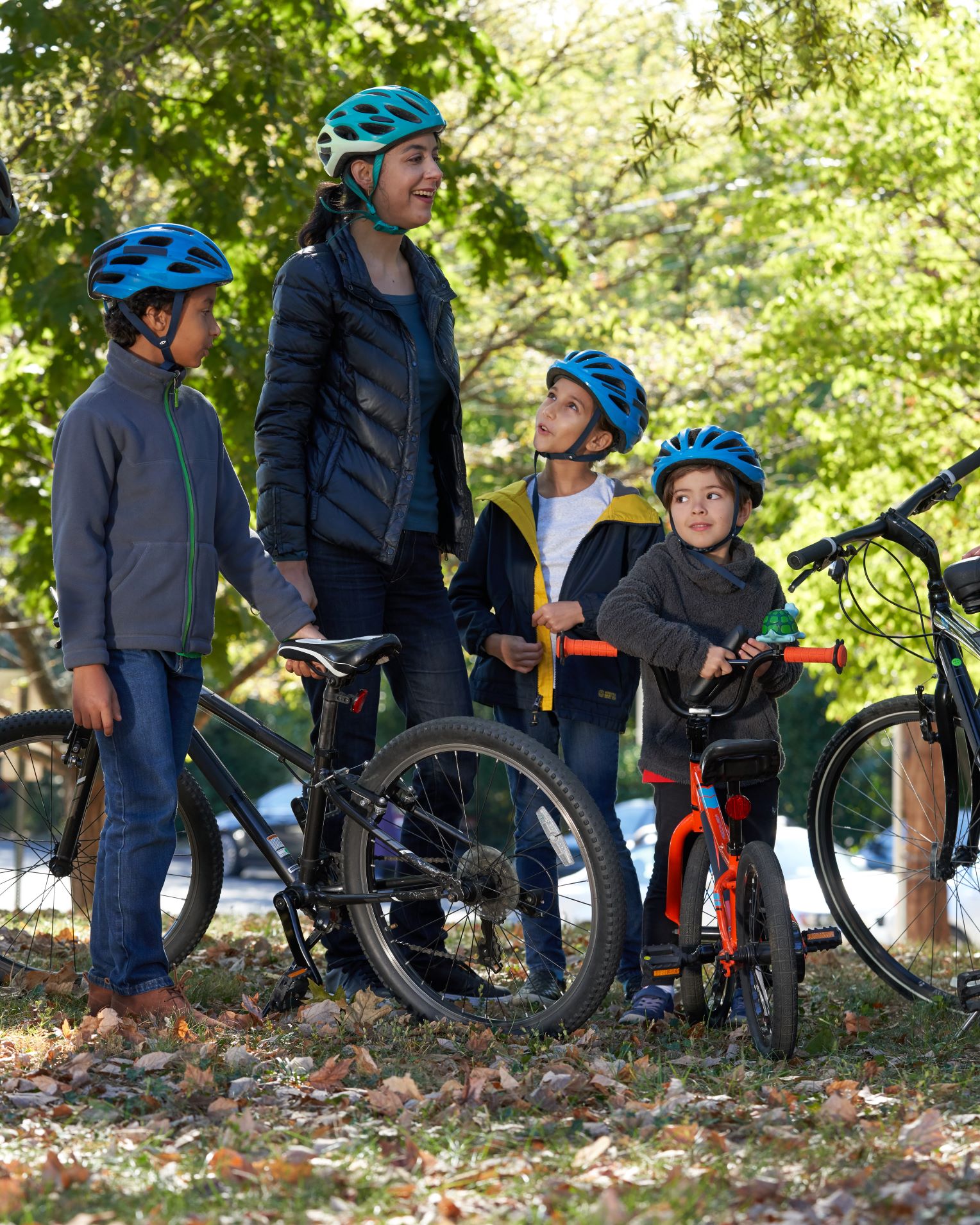 mom and young children wearing helmets with bikes