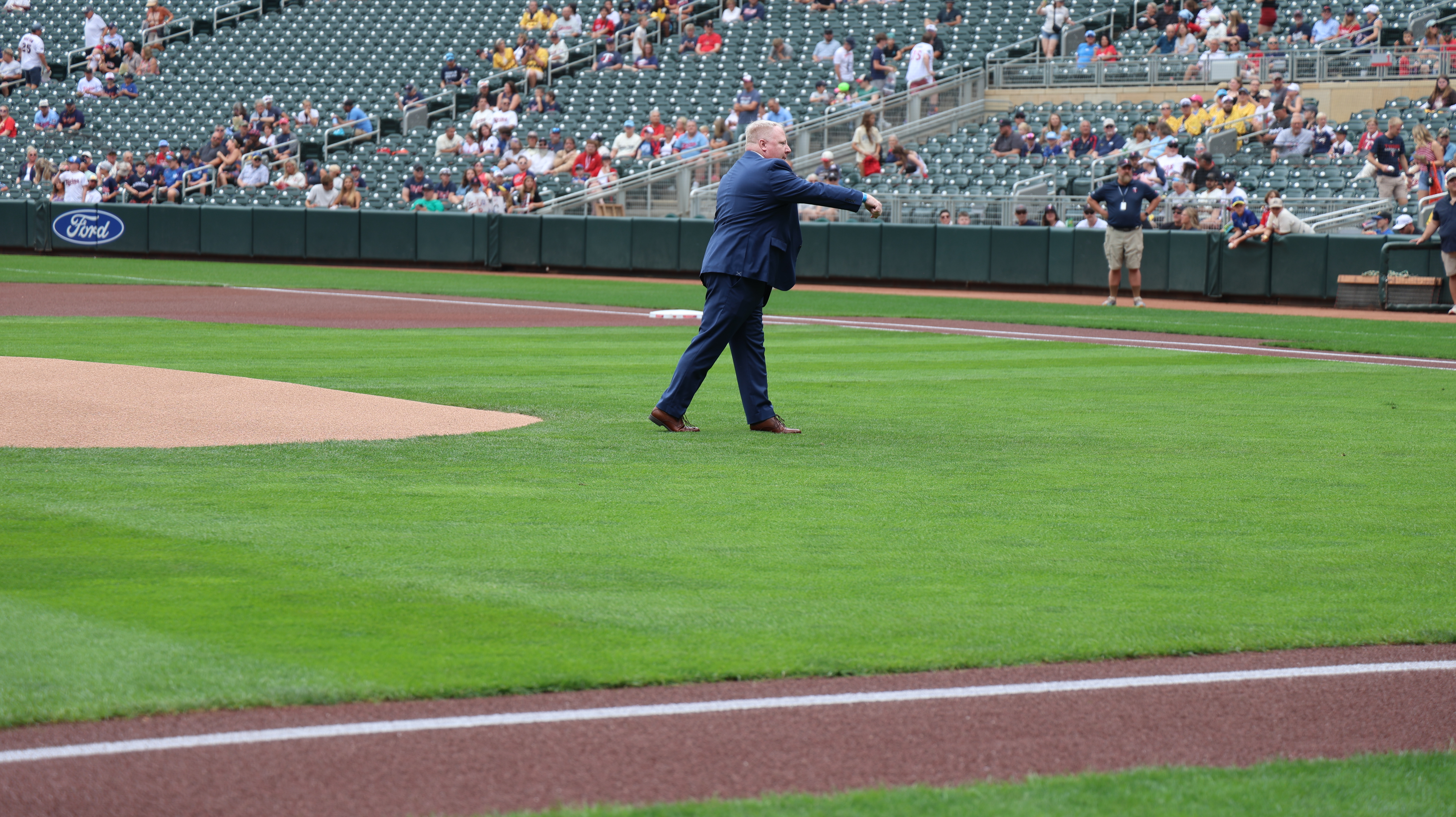 A man in a suit throws the first pitch at the twins stadium.