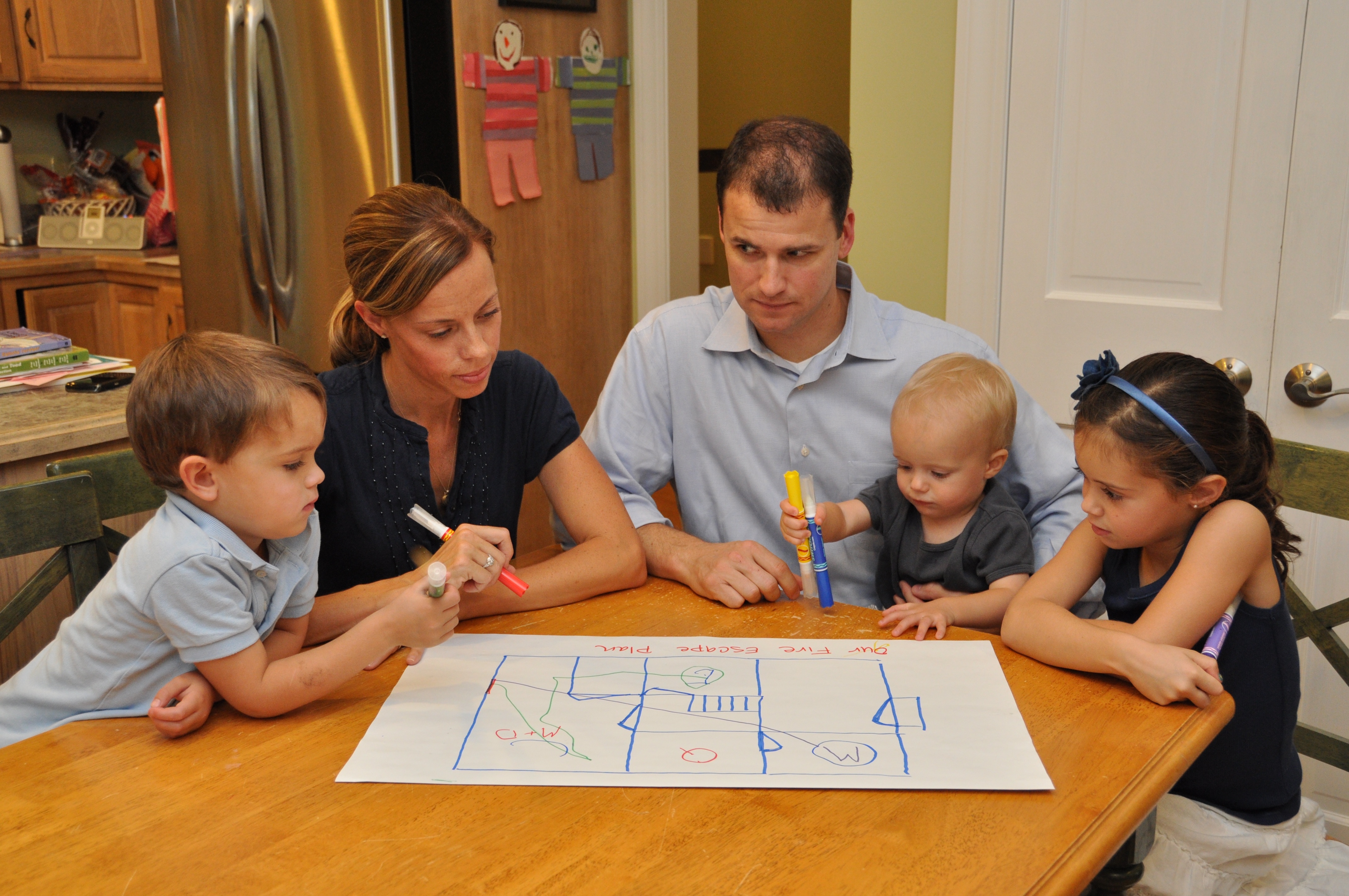 A family sits at a table talking about their fire escape plan. 
