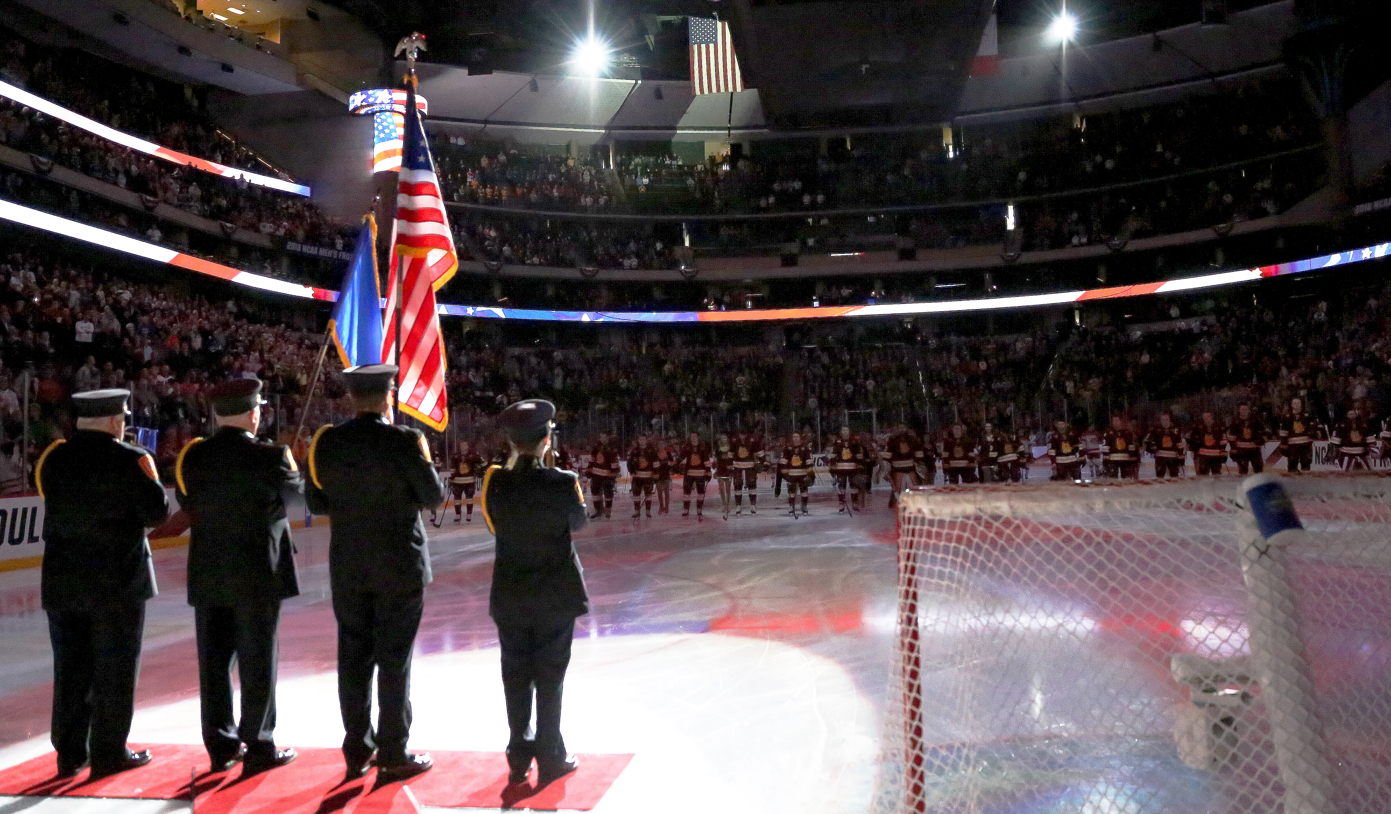 The honor guard holds a U.S. flag on the ice at a hockey game. 