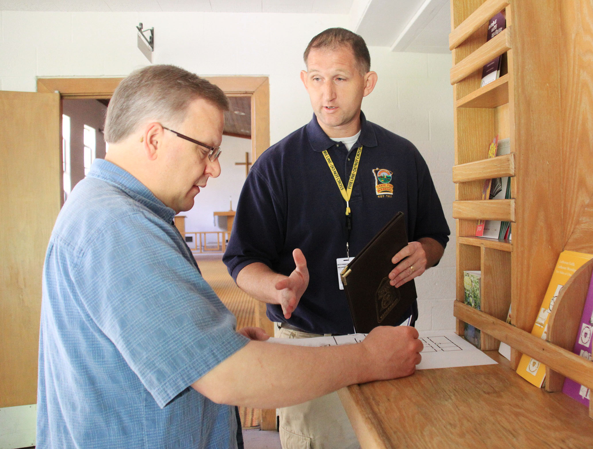 A State Fire Marshal inspector speaks with someone at a school while doing an inspection. 