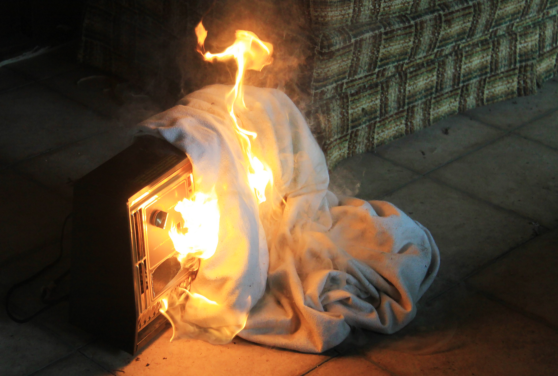 Photo of a blanket on a space heater on fire. 
